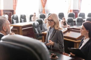 A person in civilian clothes stands next to a defense attorney before a judge in a courtroom.