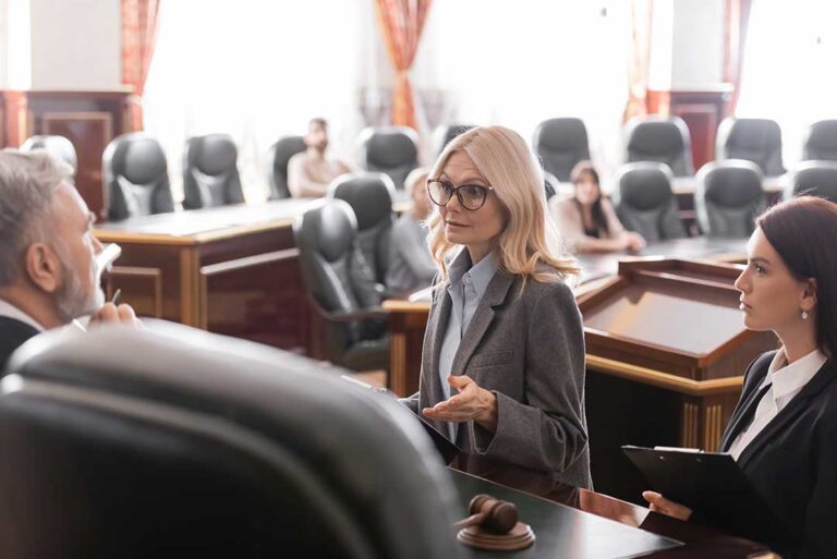 A person in civilian clothes stands next to a defense attorney before a judge in a courtroom.